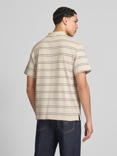 Männermodel trägt Regular Fit Poloshirt mit Logo-Stitching von Calvin Klein Jeans, beige mit dunklen Streifen, Reine Baumwolle, Rückenlänge 69 cm, Ganzkörperansicht Rückansicht.