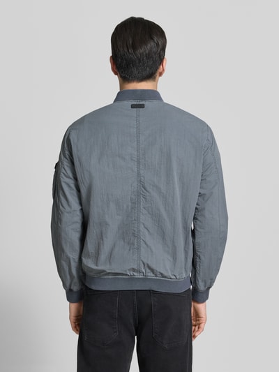 Männermodel trägt grauen Herren Blouson mit Label-Patches Modell 'IBE' von khujo, Stehkragen, Reißverschluss, Rückenansicht, Textur leicht strukturiert