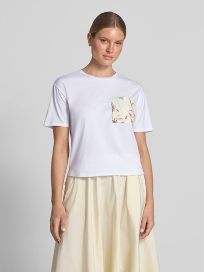 Frauenmodel trägt T-Shirt mit Rundhalsausschnitt und Brusttasche von Fynch-Hatton, weiß, florale Muster, Relaxed Fit, Ganzkörperansicht von vorne, Baumwoll-Mix mit Viskose-Anteil, Rückenlänge bei Größe S 60 cm.