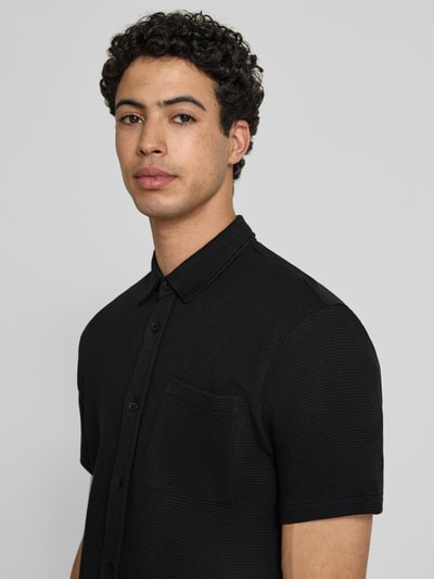 Männermodel trägt zwart regular fit vrijetijdsoverhemd van puur katoen, model 'FILLIP' van Blend met structuurpatroon, kentkraag, borstzak en knoopsluiting, Nahaufnahme Oberkörper.