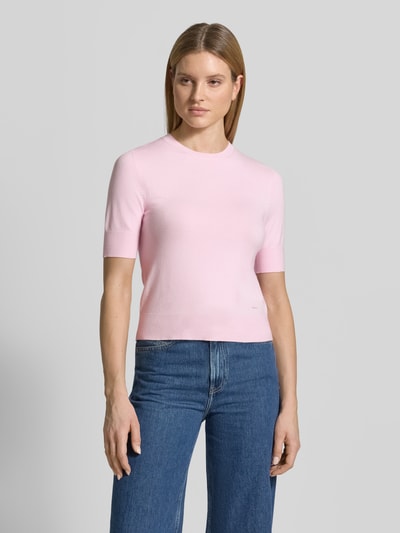 Kobiece model prezentuje Slim Fit T-Shirt aus Viskose-Mix od s.Oliver RED LABEL, jasnoróżowy, imitacja dzianiny, krój slim fit, okrągły dekolt, krótki rękaw, aplikacja z metką, drobny splot, mieszanka wiskozy, widok całej sylwetki z przodu.