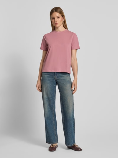Frauenmodel trägt Damen T-Shirt mit Rundhalsausschnitt Modell 'NORA' von VILA aus Baumwoll-Elasthan-Mix, Regular-Fit, Farbe Rosa, Rückenlänge bei Größe S 60 cm, Jeans, Schuhe, neutrale glatte Textur, Ganzkörperansicht von vorne.