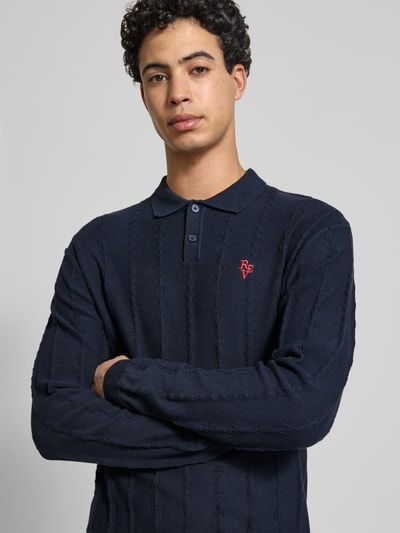 Männermodel trägt Strickpullover mit Strukturmuster und Polokragen von REVIEW, reine Baumwolle, Slim-Fit, Logo-Bestickung, Nahaufnahme Oberkörper.