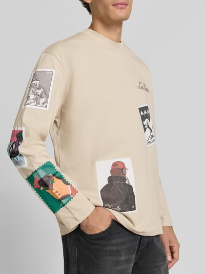 Männermodel trägt Longsleeves mit Motiv-Prints Modell 'Stamp' von Les Deux in Beige, gerippter Rundhalsausschnitt, Ganzkörperansicht von vorne, Baumwoll-Mix mit Stretch-Anteil, Straight Fit, Rückenlänge bei Größe M 70 cm.