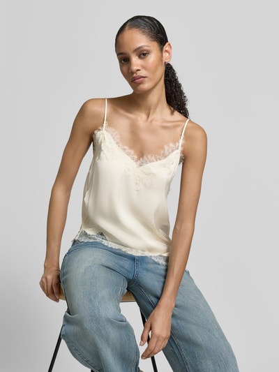 Frauenmodel trägt Blusentop mit Spaghettiträger von Mango in Creme mit Spitzenbesatz, lockerer Schnitt, Nahaufnahme Oberkörper.