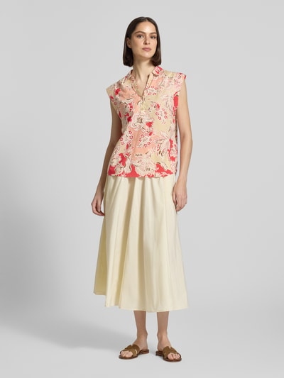 Frauenmodel trägt Blusentop mit kurzer Knopfleiste Modell 'FALDINE' von Soyaconcept aus Reine Baumwolle, Straight Fit, Kentkragen, V-Ausschnitt, Rückenlänge 64 cm, Ärmellänge 5 cm, florale Muster in Rot und Beige, Ganzkörperansicht von vorne.