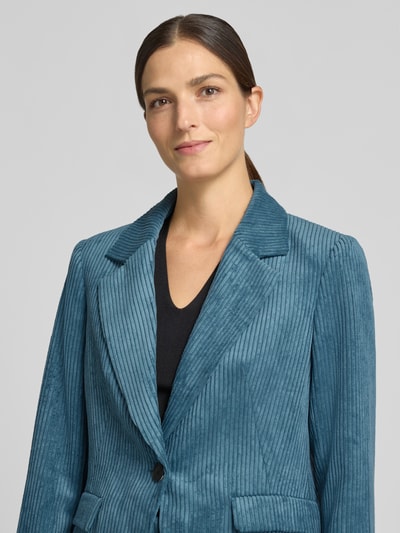 Frauenmodel trägt Slim Fit Blazer aus Cord mit Pattentaschen von COMMA in Blau, strukturierte Oberfläche, Nahaufnahme Oberkörper.