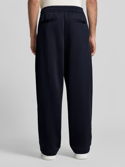 Männermodel trägt Wide Fit Sweathose mit elastischem Bund von Armani Exchange, dunkelblau, Baumwoll-Mix, Gesäßtaschen, Ganzkörperansicht Rückansicht.
