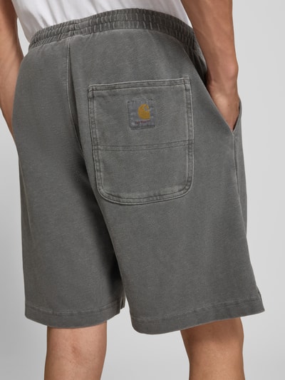 Männermodel trägt Regular Fit Shorts mit elastischem Bund Modell 'Harper' von Carhartt Work In Progress aus Reine gewachste Baumwolle, dezentes Grau, strukturierte Oberfläche, Herren Shorts, Ganzkörperansicht Rückansicht.