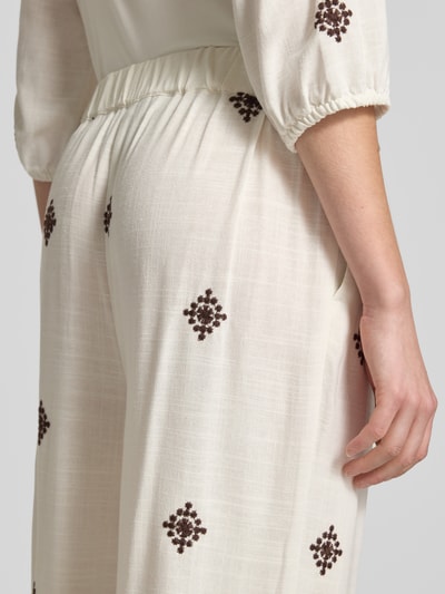Frauenmodel trägt Hose aus Viskose-Leinen-Mix mit Stitchings von Christian Berg Woman Selection, cremefarben mit braunem Muster, Nahaufnahme Rückansicht. Regular Fit, elastischer Bund, leichte und strukturierte Textur.