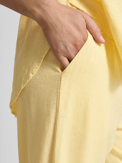 Frauenmodel trägt Wide-Leg-Pants mit elastischem Bund Modell 'Lava' von FREE/QUENT aus Leinen-Mix mit Viskose-Mix, seitliche Eingrifftaschen, Struktur fein, Farbe Gelb, Loose-Fit, Nahaufnahme Hüfte und Hand in Tasche, Ganzkörperansicht Detailaufnahme