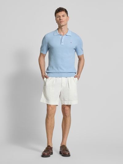 Männermodel trägt Regular Fit Poloshirt mit Label-Stitching von Gant aus reiner Baumwolle, hellblau, Polokragen, Ganzkörperansicht von vorne.