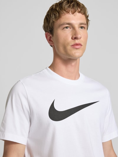 Männermodel trägt Herren T-Shirt aus Reine Baumwolle, Gerader-Schnitt, Modell 'Swoosh' von Nike mit Logo-Print, Rundhalsausschnitt, Nahaufnahme Oberkörper. Rückenlänge bei Größe M: 73 cm.