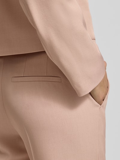Vrouwenmodel draagt Stoffhose mit Gesäßtasche van Jake*s Collection in beige, losse fit, materiaal-mix, detailopname heupen.