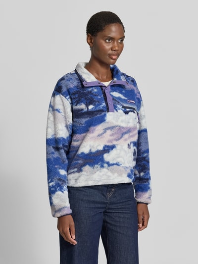 Vrouwenmodel draagt Fleeceshirt met opstaande kraag en labelpatch Model 'Helvetia II' van Columbia in blauw-witte Fleece, straight fit, borstzak met ritssluiting, zichtbare drukknopen, structuuroppervlak, voorkant geheel in beeld, ruglengte maat S 57 cm, schouderbreedte 48 cm, borstwijdte 54 cm, mouwlengte 59 cm. Ganzkörperansicht von vorne.
