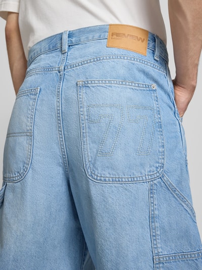 Männermodel trägt Regular Fit Jeansshorts mit Label-Details von REVIEW, hellblaue Baumwolle, 5-Pocket-Design, Ganzkörperansicht Rückansicht.