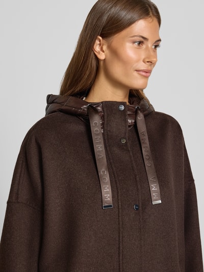 Frauenmodel trägt Jacke mit Kapuze von COMMA in Dunkelbraun mit glänzendem Kapuzendetail, Knopfleiste, wpuszczane kieszenie, luźny krój, Długość tyłu w rozmiarze S: 73 cm, Szerokość ramion w rozmiarze S: 70 cm, Szerokość klatki piersiowej w rozmiarze S: 65 cm, Długość rękawów w rozmiarze S: 45 cm, Nahaufnahme Oberkörper