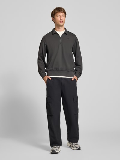 Männermodel trägt Regular Fit Sweatshirt aus reiner Baumwolle von G-Star RAW in Dunkelgrau, glatte Struktur, Ganzkörperansicht von vorne.