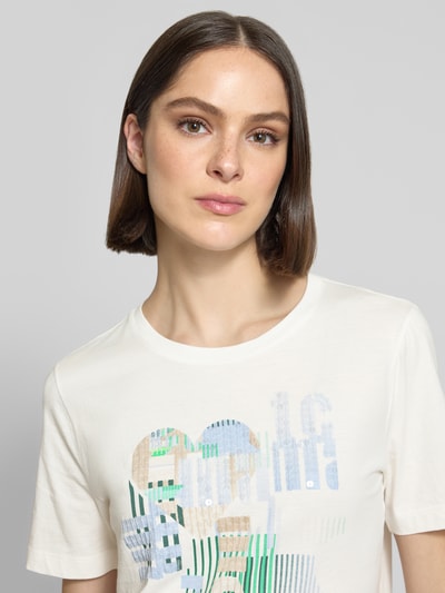 Frauenmodel trägt Damen T-Shirt mit Motiv-Print und Pailletten von Marc Cain in Reine Baumwolle, Regular-Fit, Rundhalsausschnitt, Nahaufnahme Oberkörper.
