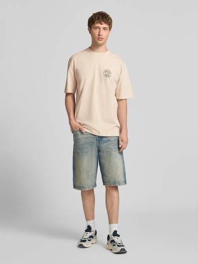 Männermodel trägt Oversized T-Shirt mit Label-Print von Pegador, beige, Reine Baumwolle, Rundhalsausschnitt, Rückenlänge 72 cm, Ganzkörperansicht von vorne.