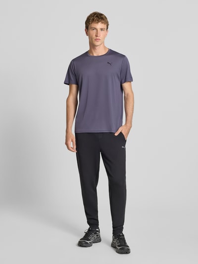 Männermodel trägt Regular Fit Sport-T-Shirt mit Logo-Print Modell 'TAD Essential' von PUMA in Anthrazit, Herren Sport-T-Shirt, Ganzkörperansicht von vorne.