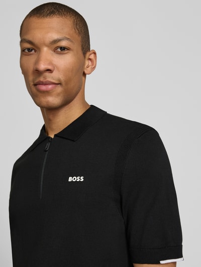 Męski model nosi Regular Fit Poloshirt aus reiner Baumwolle Modell 'KN_EVER-X' von BOSS Green, efekt: jednolity kolor, krótki rękaw, kołnierzyk polo, dekolt w serek z krótkim zamkiem błyskawicznym, aplikacja z marką, drobny splot, czarna bawełna, całkowity skład: bawełna, nahaufnahme górnej części ciała.