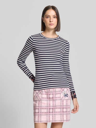 Kobiece model prezentuje bluzkę z długim rękawem Slim Fit Longsleeve aus Baumwoll-Mix od Marc Cain, mieszanka bawełny, okrągły dekolt, kwiatowy detal, długość tyłu w rozmiarze 36: 57 cm, widok całej sylwetki z przodu