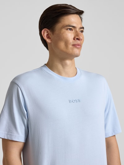 Männermodel trägt Regular Fit T-Shirt aus reiner Baumwolle Modell 'TEE 10' von BOSS Green in Hellblau mit Label-Applikation, Nahaufnahme Oberkörper.