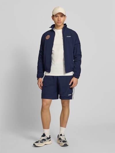 Männermodel trägt Shorts mit Label-Stitching Modell 'Slipstream' von PROHIBITED in Dunkelblau, Regular Fit, Ganzkörperansicht von vorne.
