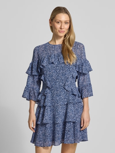 Frauenmodel trägt Minikleid mit Volants von MICHAEL Michael Kors in A-Linie, Allover-Look, Rundhalsausschnitt, Ganzkörperansicht von vorne. Rückenlänge bei Größe S: 86 cm, Brustweite bei Größe S: 44 cm, Ärmellänge bei Größe S: 32 cm.