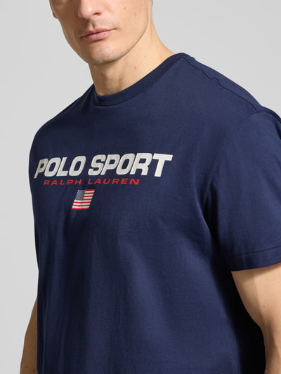 Mannenmodel draagt Relaxed Fit T-Shirt uit zuiver katoen van Polo Ralph Lauren, effen donkerblauw met labelprint, ronde hals, korte mouw, close-up bovenlichaam.