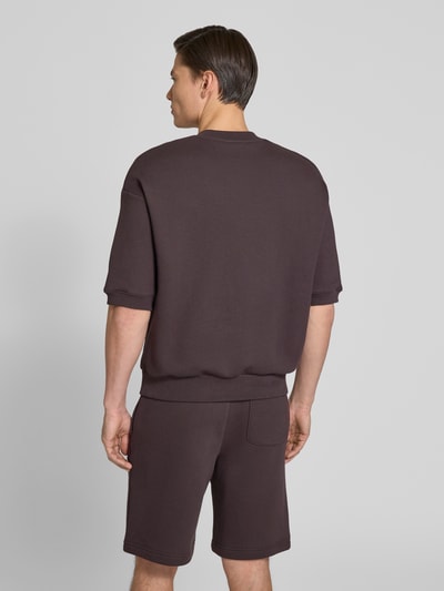 Männermodel trägt Relaxed Fit Sweatshirt aus reiner Baumwolle von Lacoste, efekt: jednolity kolor, krój relaxed fit, wyhaftowane logo, okrągły dekolt, długi rękaw, prążkowane zakończenia rękawów i dołu, dzianina dresowa, bawełna, Ganzkörperansicht Rückansicht.
