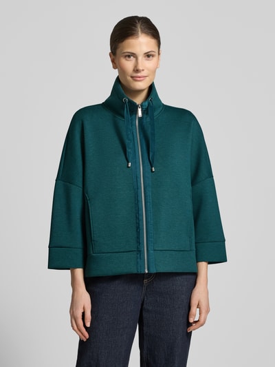 Vrouwenmodel draagt Boxy Fit Sweatjacke met Viskose-Anteil van Tom Tailor in effen groen, scuba textuur, met rits, labelprint op tunnelkoordjes, opstaande kraag, driekwart mouwen, zijzakken, geheellichaamsaanzicht van voren.