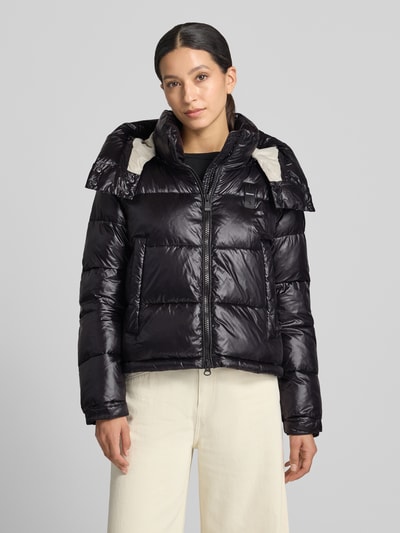 Frauenmodel trägt Regular Fit Jacke mit Sorona-Füllung Modell 'GLORIA' von Blauer USA in Schwarz, glänzende Stepp-Optik, Stehkragen mit Kapuze, Eingrifftaschen, Zweiwege-Reißverschluss, Logo-Detail, Ganzkörperansicht von vorne.