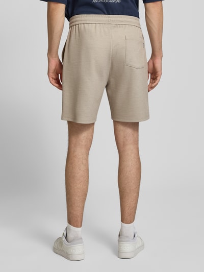 Mężczyzna nosi Straight Fit Shorts mit Viskose-Anteil von REVIEW w beżowym kolorze, elastyczna mieszanka materiałów, tunel, szerokość w rozmiarze M: 43 cm, długość wewnętrzna nogawki: 19 cm, widok całej sylwetki z tyłu.