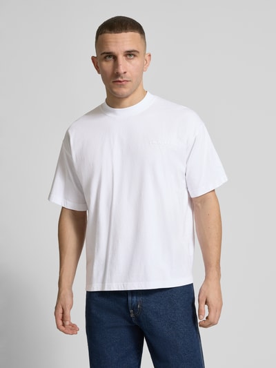 Männermodel trägt weißes Regular Fit T-Shirt mit Logo-Detail von ANOTHER COTTON LAB aus reiner Baumwolle, Ganzkörperansicht von vorne.
