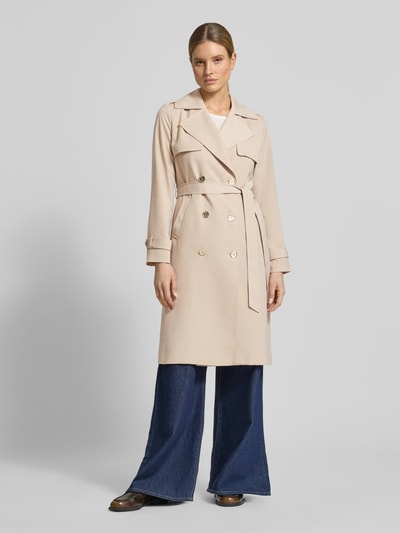 Vrouwenmodel draagt Zweireihiger Trenchcoat mit Bindegürtel van MICHAEL Michael Kors in beige, regular fit, met dubbele rij knopen, reverskraag, strikceintuur, gladde textuur, ruglengte maat S 47 cm, schouderbreedte 40 cm, borstwijdte 50 cm, mouwlengte 63 cm. Ganzkörperansicht van voren.