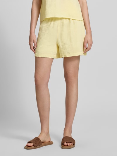 Kobiece model nosi szorty Comfort Fit Shorts aus reiner Baumwolle Modell 'SASTINA' od Pieces, efekt: jednolity kolor, muślin, bawełna, wpuszczane kieszenie, tunel, elastyczny pas, kolor jasny żółty, wykończenie materiału muślin, widok całego ciała od przodu