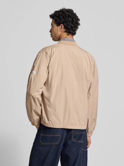 Männermodel trägt Regular Fit Bomberjacke mit College-Kragen Modell 'BELVEDERE' van Pepe Jeans, effen beige, elastische boorden, zijzakken, label patch, geheel kleur, langem mouw, rits, Ganzkörperansicht Rückansicht.