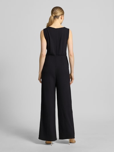 Frauenmodel trägt schwarzen Jumpsuit mit Bindegürtel Modell 'Jessica' von GUIDO MARIA KRETSCHMER WOMAN, Taillierter Schnitt, Rückenreißverschluss, Ganzkörperansicht Rückansicht.