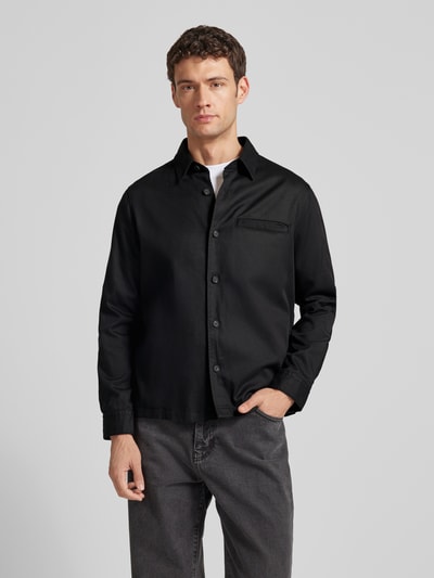 Männermodel trägt Regular Fit Hemdjacke aus Lyocell-Baumwoll-Mix Modell 'ENOCK' von HUGO in Schwarz, Ganzkörperansicht von vorne.