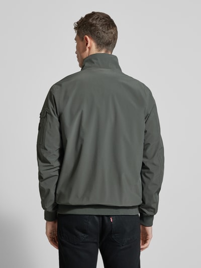 Männermodel trägt Windbreaker mit Stehkragen Modell 'YETUR' von CARS JEANS in Grau, Reißverschlusstasche am Arm, Material-Mix, Ganzkörperansicht Rückansicht.
