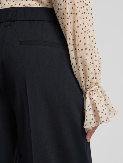 Frauenmodel trägt Barrel Fit Hose Modell 'Moira Bloom' von OPUS PANTS, dunkelblauer Baumwoll-Mix mit Bügelfalten, Detailaufnahme Rückansicht.