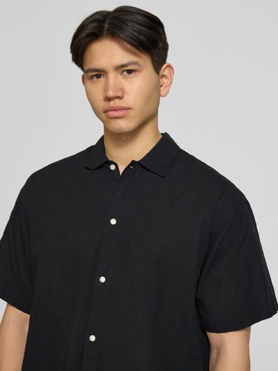 Männermodel trägt Regular Fit Freizeithemd aus Baumwoll-Leinen-Mix von Jack & Jones, schwarz, Kentkragen, Knopfleiste, Nahaufnahme Oberkörper.
