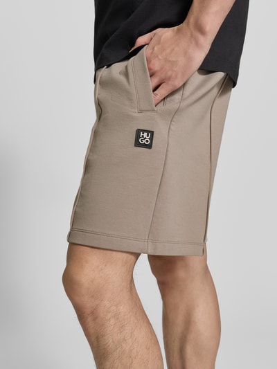 Männermodel trägt Regular Fit Sweatshorts aus katoenmix model 'DIMACSHORT' van HUGO, look: effen, labelpatch, boord met tunnelkoord, zij-steekzakken, materiaalverwerking: sweat, kort detailopname zijkant bovenbeen.