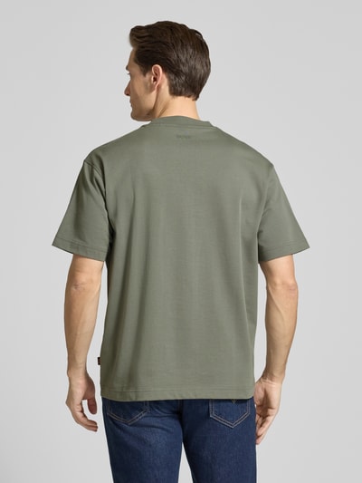 Männermodel trägt Regular Fit T-Shirt aus reiner Baumwolle Modell 'TEETIMM' von BOSS Orange in Olivgrün, unifarben, Ganzkörperansicht Rückansicht.
