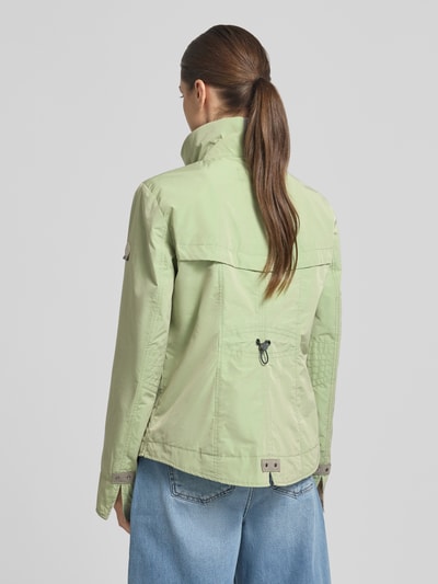 Frauenmodel trägt Regular Fit Jacke mit Logo-Patch von Gil Bret in Hellgrün, Reißverschlusstaschen, Stehkragen, Rückenansicht, Ganzkörperansicht Rückansicht. Rückenlänge 64 cm, Schulterbreite 41 cm, Brustweite 46 cm, Ärmellänge 65 cm.