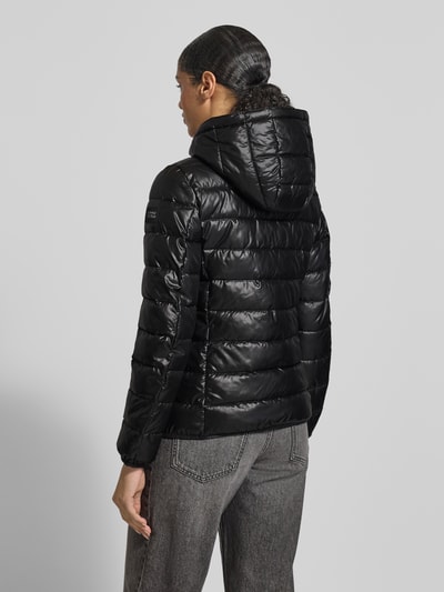 Frauenmodel trägt schwarze Jacke mit Kapuze von NAUTGÅRD, lockerer Schnitt, Label-Detail, Rückenansicht, Ganzkörperansicht Rückansicht.