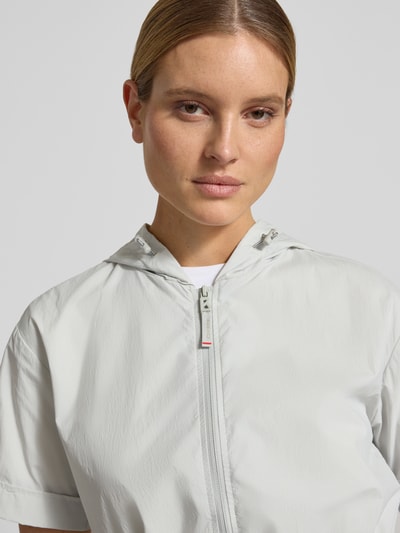 Modelka kobieca nosi Knielanges Kleid mit Zweiwege-Reißverschluss Modell 'RONNY2' od FIRE + ICE, kolor jasnoszary, prosta faktura, kaptur, długość do kolan, krój regular fit, Szerokość w rozmiarze 36: 49 cm, długość tyłu: 96 cm, długość rękawa: 21 cm, zbliżenie na górną część ciała.