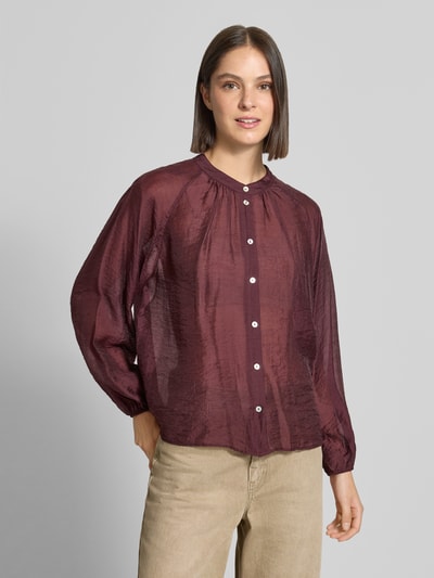 Frauenmodel trägt Oversized Langarmbluse aus Lyocell-Mix Model 'Fabrielle' von OPUS in Dunkelrot, leicht glänzende Textur, beige Hose, Nahaufnahme Oberkörper. Damen Langarmbluse von OPUS.